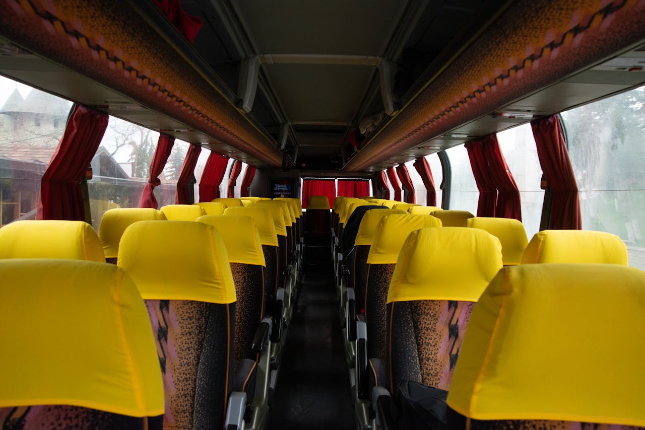 Spacious bus interior featuring bright yellow seats and red curtains, ideal for travel and transportation imagery.